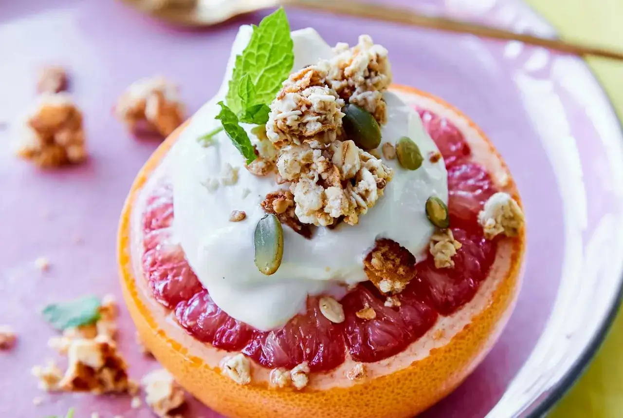 Grapefrukt fylld med yoghurt, granola och pumpafrön. En hälsosam frukost för diabetiker.