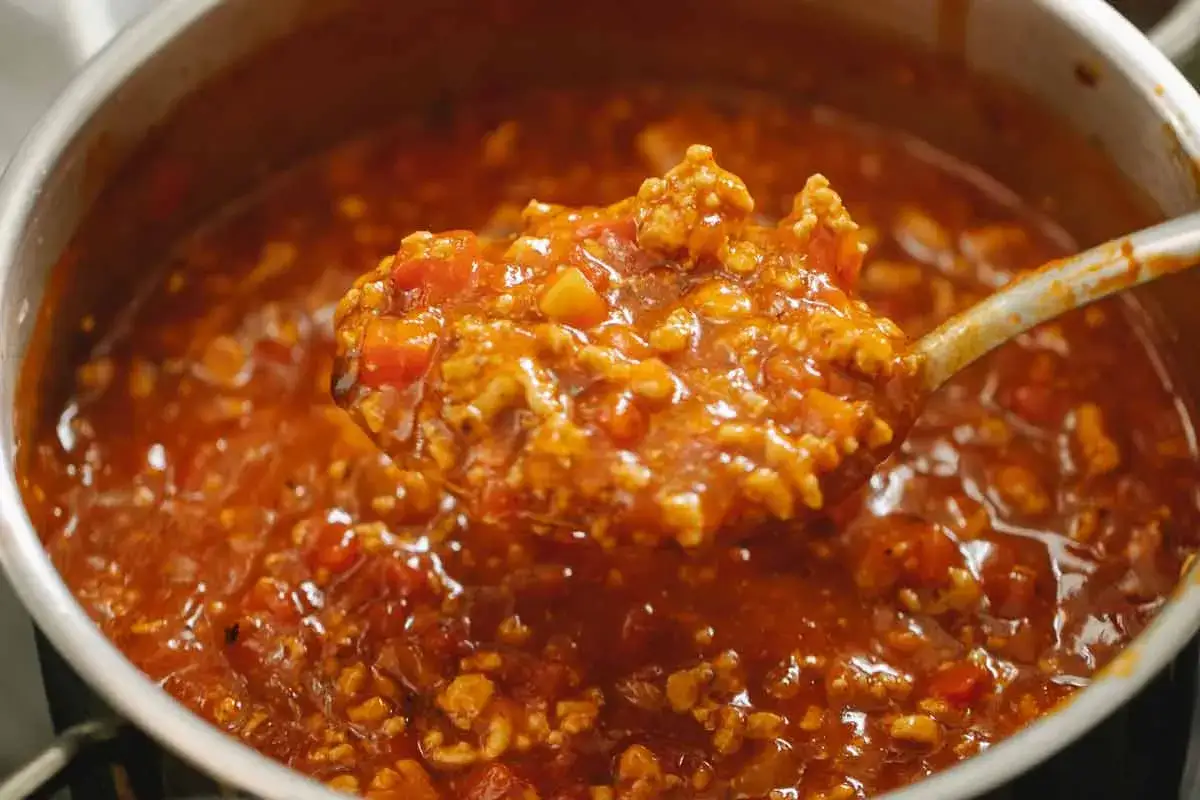 En sked tar upp en portion av en mustig k&ouml;ttf&auml;rss&aring;s, perfekt f&ouml;r kalorisn&aring;la recept under 300.