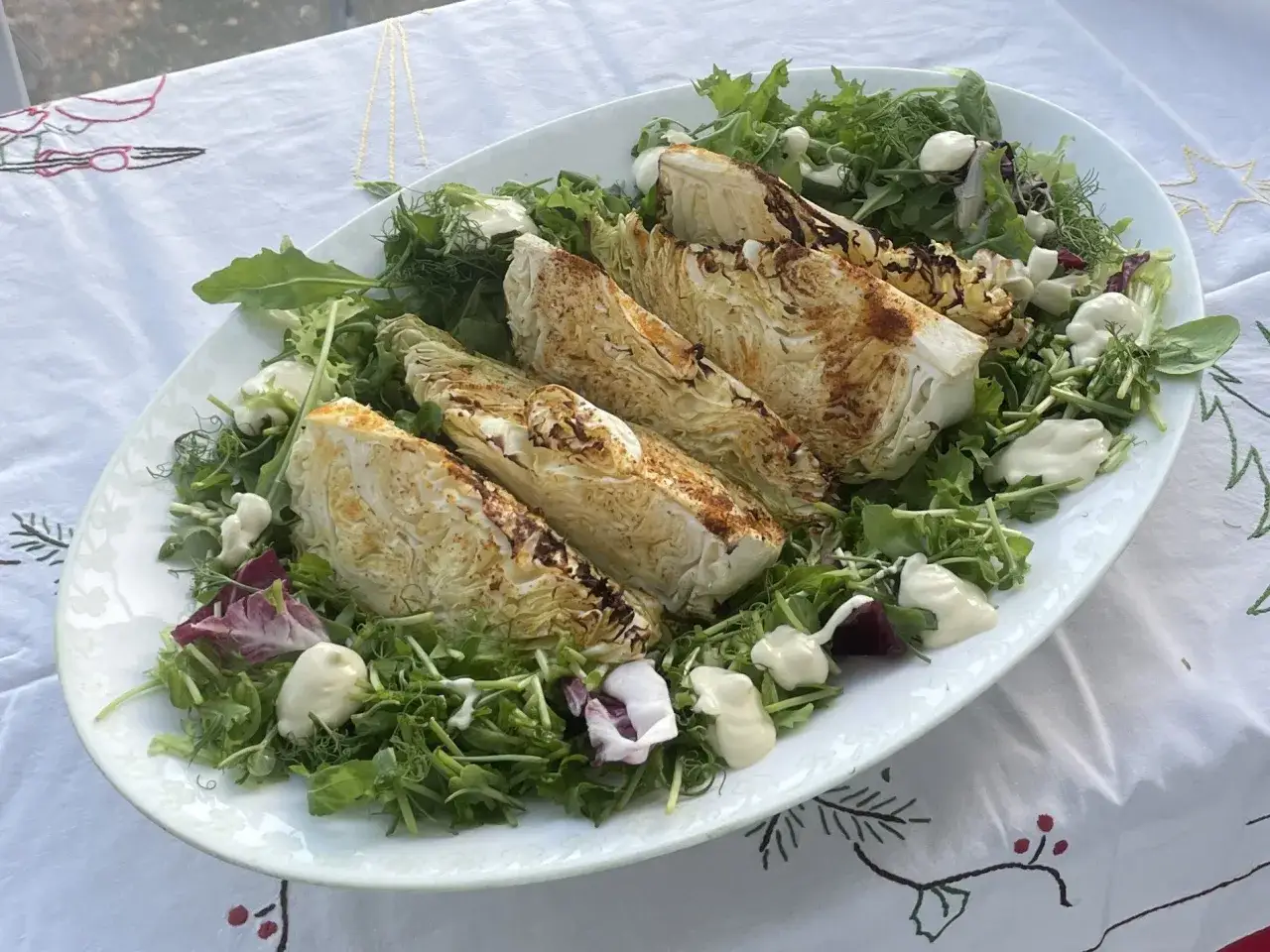 Ugnsrostad spetskål serverad på en bädd av gröna blad med en krämig dressing. Spetskål nyttigt och gott!