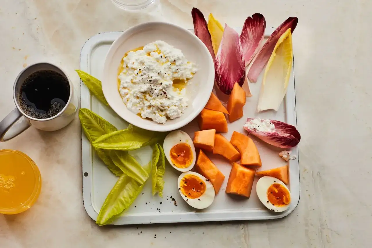 Frukostbricka med keso, &auml;gg, melon, endiver och kaffe. En h&auml;lsosam start kan minska risk f&ouml;r biverkningar av socker.