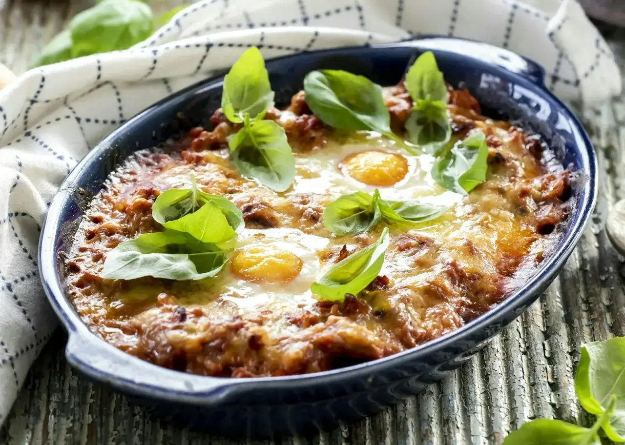 En proteinrik mat recept: en ugnsbakad rätt med köttfärs, ost och ägg, toppad med färsk basilika.
